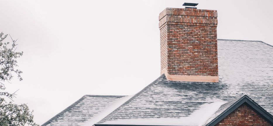 Chimney on snowy roof of brick house in Knox City, TX, serene winter scene